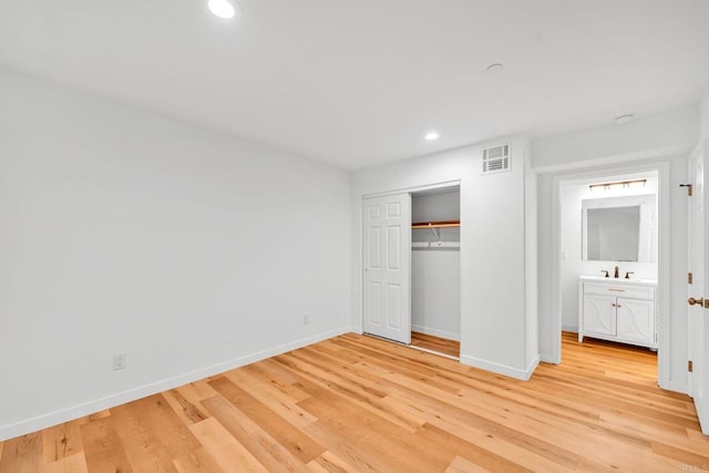 unfurnished bedroom featuring light wood-type flooring, a closet, and sink