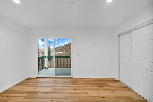 unfurnished bedroom featuring light wood-type flooring, a closet, and access to outside