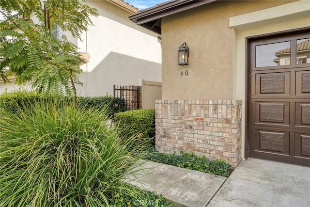 property entrance featuring a garage, fence, and stucco siding