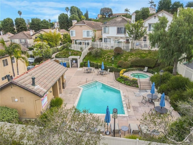 community pool featuring a hot tub, a residential view, fence, and a patio