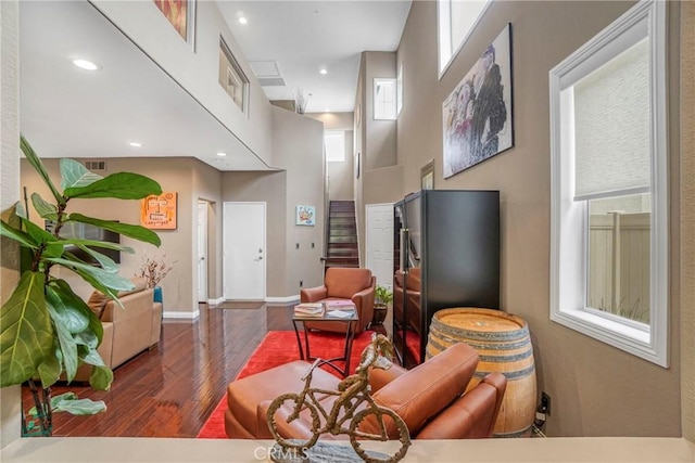 living area with baseboards, a high ceiling, dark wood-style flooring, and recessed lighting