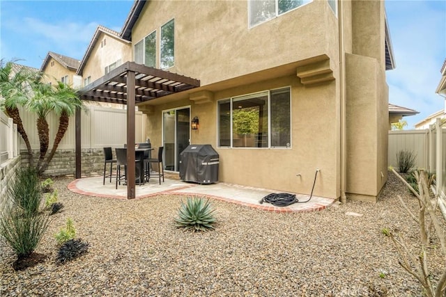 rear view of house featuring a patio, stucco siding, a fenced backyard, and a pergola