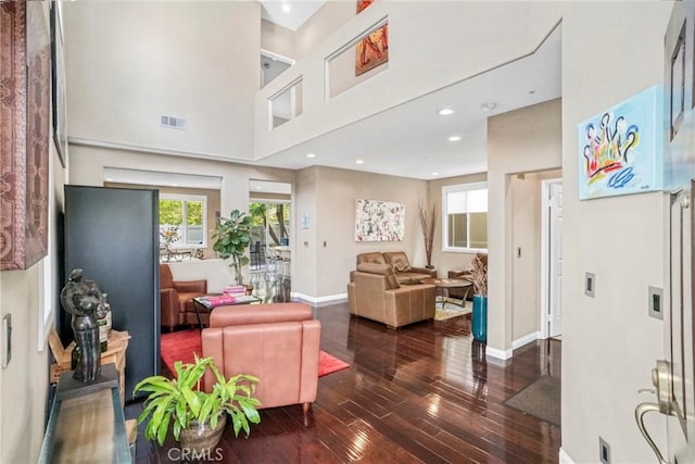 living room with recessed lighting, dark wood-style flooring, a towering ceiling, visible vents, and baseboards