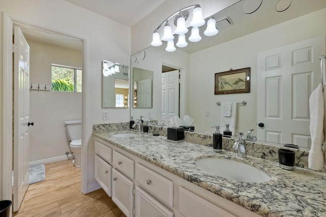 bathroom featuring a sink, baseboards, toilet, and double vanity