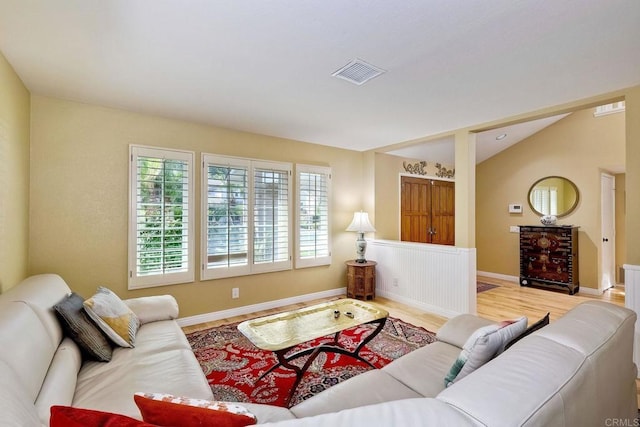 living room with vaulted ceiling, wood finished floors, visible vents, and baseboards