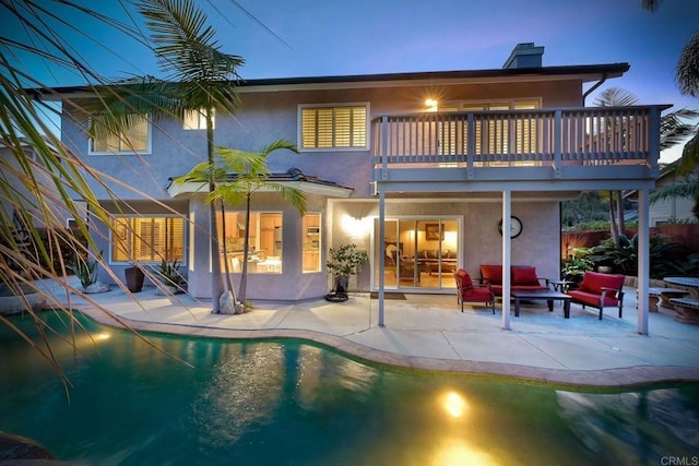 rear view of house with stucco siding, an outdoor pool, a chimney, and a patio