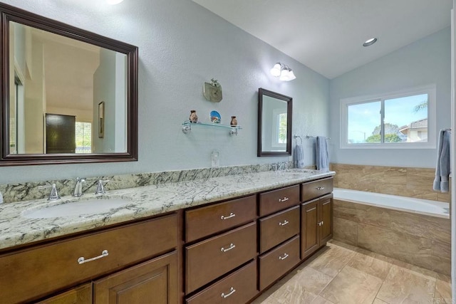 bathroom with a sink, lofted ceiling, a garden tub, and double vanity