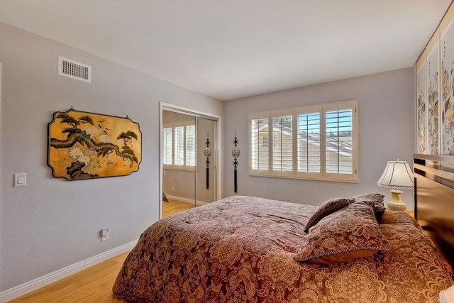 bedroom featuring visible vents, baseboards, a closet, and light wood-style flooring