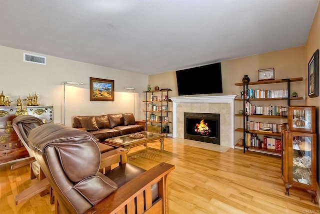 living area with visible vents, a fireplace, and light wood finished floors