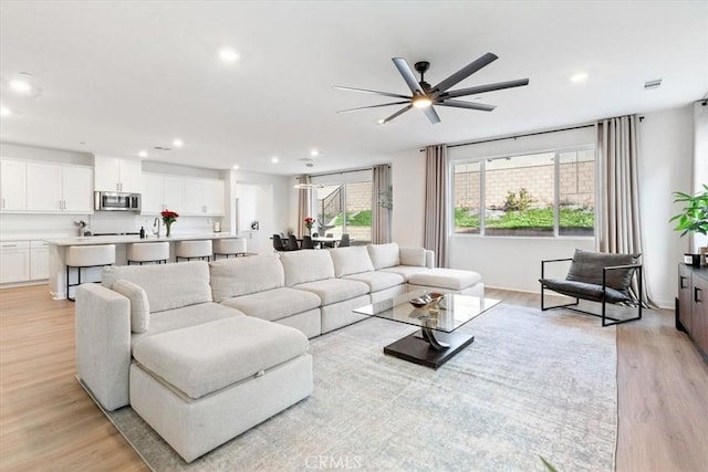 living room featuring recessed lighting, a ceiling fan, and light wood-style floors
