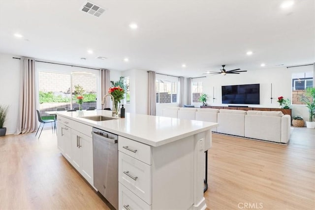 kitchen featuring light wood finished floors, a sink, visible vents, dishwasher, and an island with sink