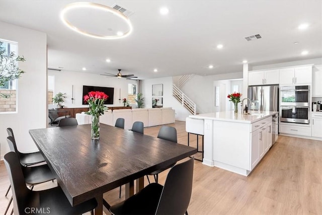 dining room with light wood finished floors, recessed lighting, visible vents, and stairway