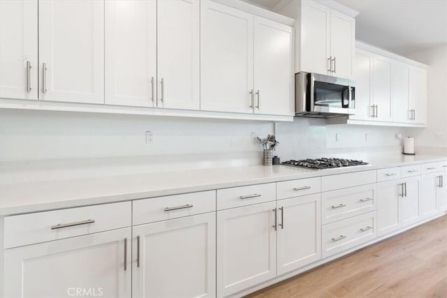kitchen with white cabinets, light wood-style flooring, stainless steel appliances, and light countertops