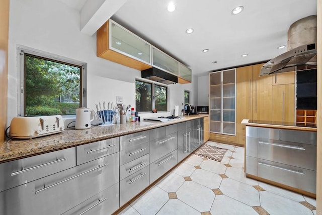 kitchen featuring light stone countertops, modern cabinets, glass insert cabinets, and recessed lighting