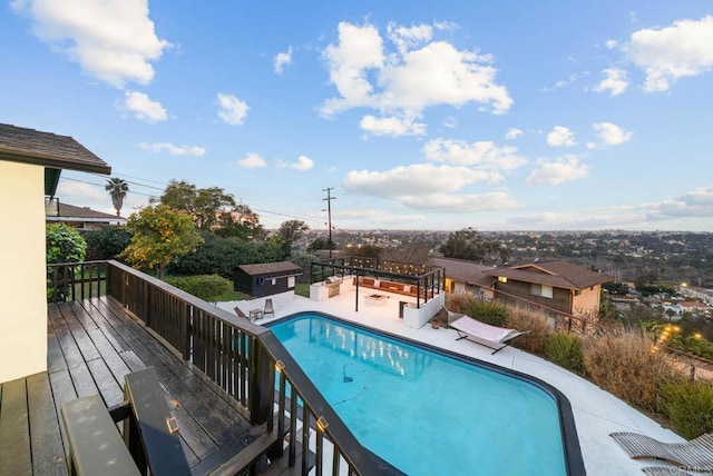 view of swimming pool featuring a patio area, an outdoor structure, a wooden deck, and a fenced in pool