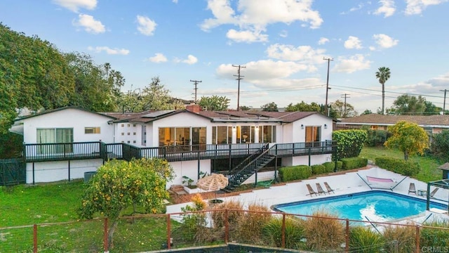 rear view of house with a patio, fence, a yard, stairway, and roof mounted solar panels