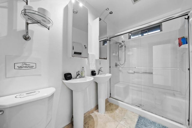 bathroom with toilet, a shower stall, and a sink