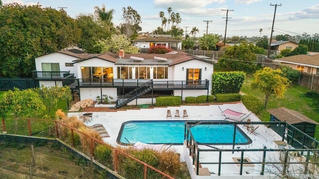 rear view of property featuring a fenced in pool, a patio area, a fenced backyard, and stairs