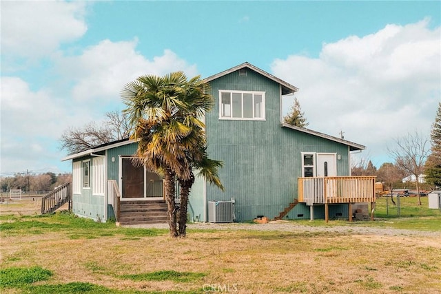 rear view of house featuring cooling unit, a lawn, and a deck