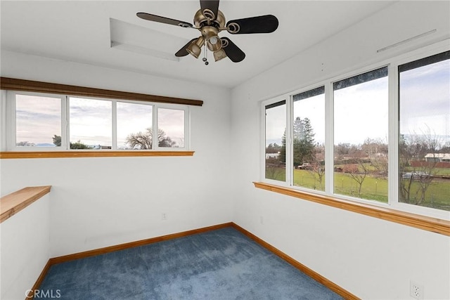 empty room featuring a ceiling fan, baseboards, and dark colored carpet