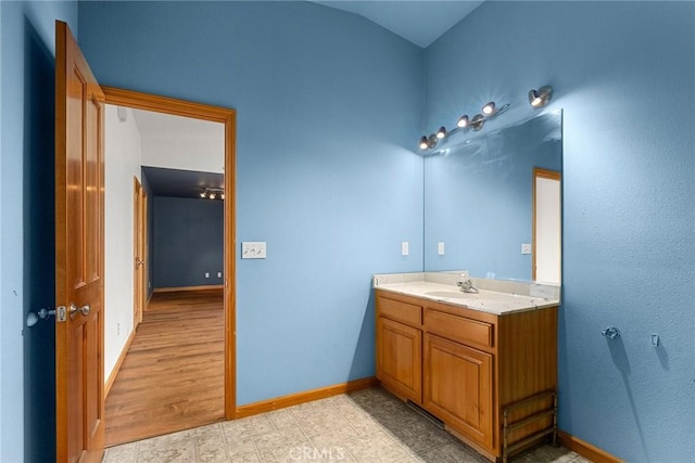 bathroom with baseboards, vaulted ceiling, and vanity