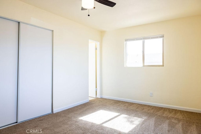 unfurnished bedroom with ceiling fan, carpet flooring, and a closet