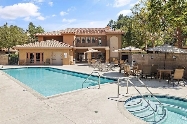 view of pool with french doors, a hot tub, and a patio