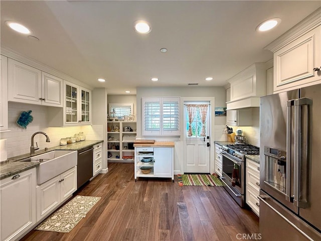 kitchen with sink, high end appliances, dark hardwood / wood-style flooring, white cabinets, and light stone countertops