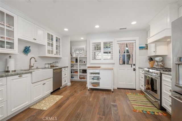 kitchen with glass insert cabinets, white cabinetry, appliances with stainless steel finishes, and light stone countertops