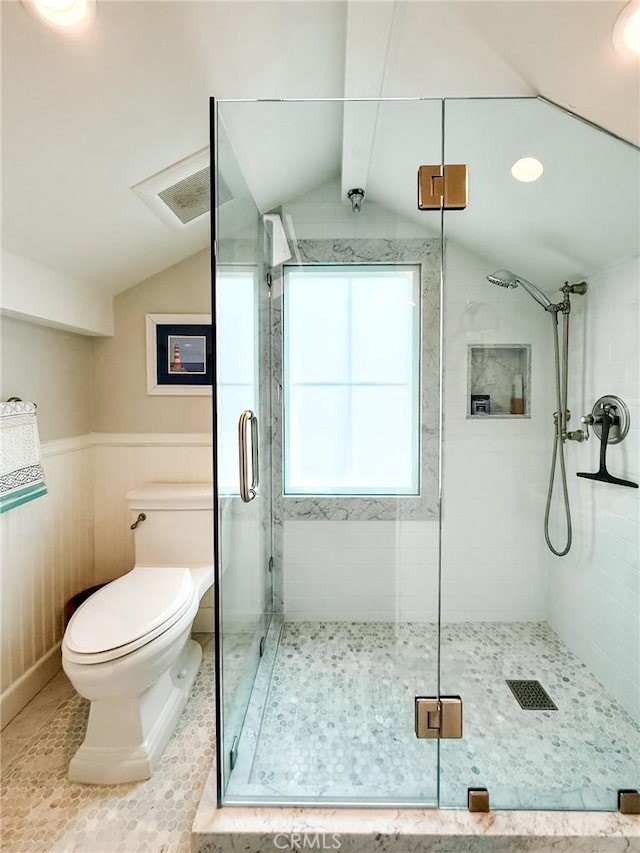 bathroom featuring toilet, a stall shower, vaulted ceiling, and tile patterned floors