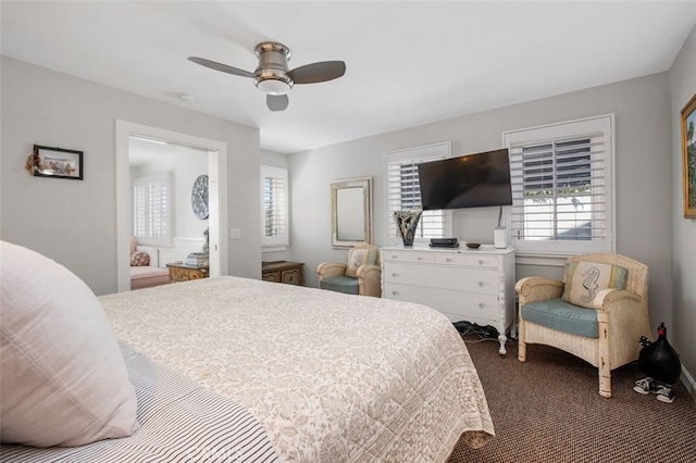 bedroom with multiple windows, dark carpet, and a ceiling fan