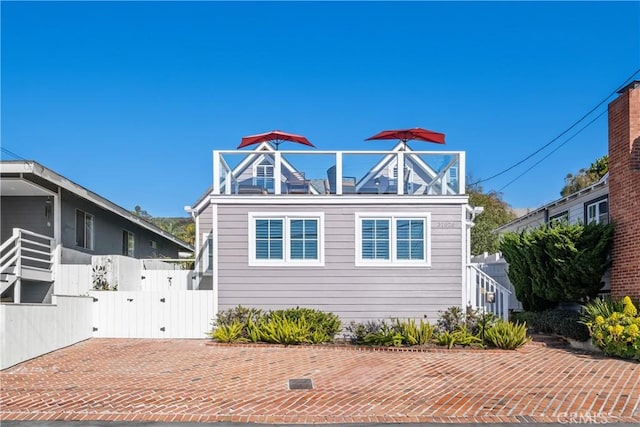 view of front of house featuring a balcony, fence, and a gate