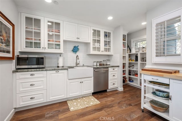 kitchen with white cabinets, glass insert cabinets, appliances with stainless steel finishes, stone counters, and a sink