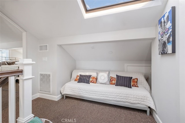 bedroom with dark colored carpet, visible vents, vaulted ceiling with skylight, and baseboards