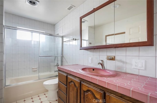 full bathroom featuring toilet, tasteful backsplash, tile walls, vanity, and enclosed tub / shower combo