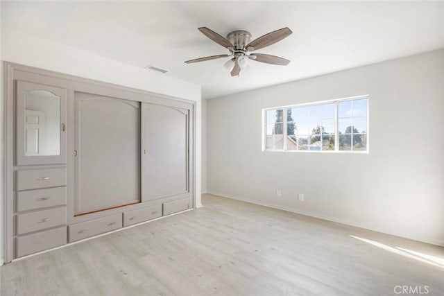 unfurnished bedroom featuring ceiling fan, light wood-type flooring, and a closet