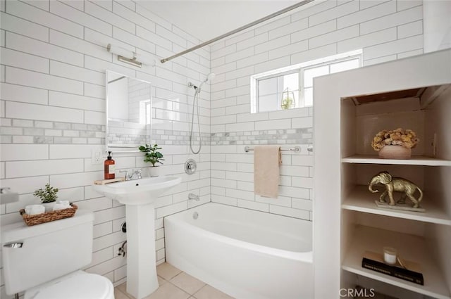 bathroom featuring tiled shower / bath combo, tile walls, tile patterned floors, and toilet