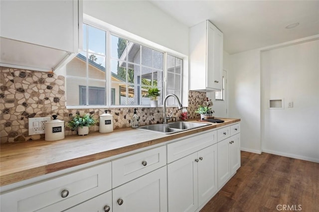 kitchen with sink, butcher block countertops, white cabinetry, dark hardwood / wood-style flooring, and backsplash