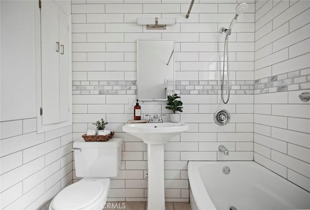 bathroom featuring tiled shower / bath, toilet, and tile walls