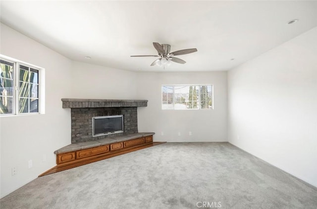 unfurnished living room featuring a brick fireplace, carpet, and ceiling fan