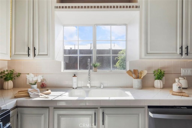 kitchen featuring white cabinetry, dishwasher, sink, and decorative backsplash