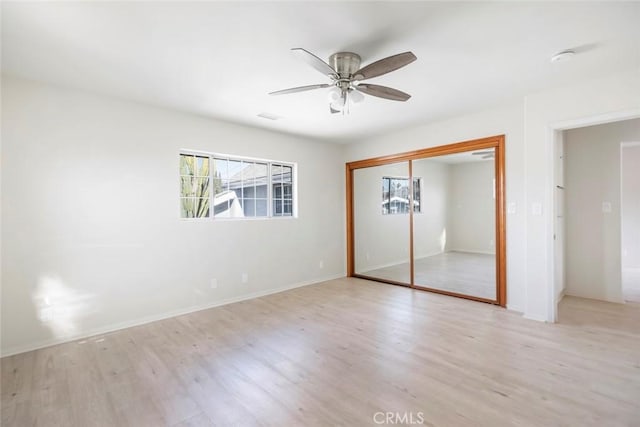 unfurnished bedroom with multiple windows, ceiling fan, light hardwood / wood-style floors, and a closet