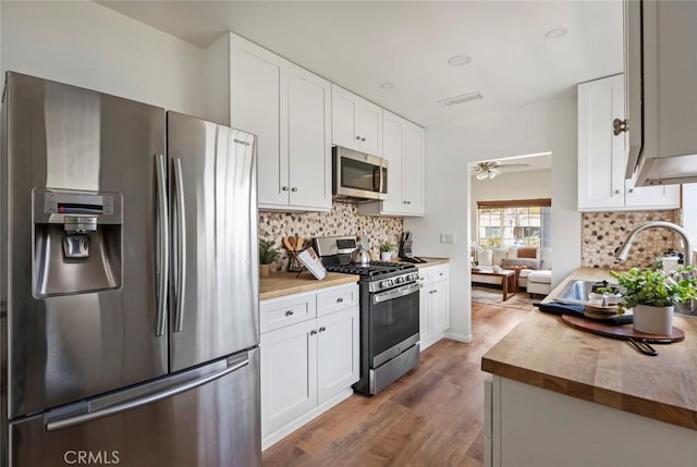 kitchen with white cabinetry, sink, stainless steel appliances, and wooden counters