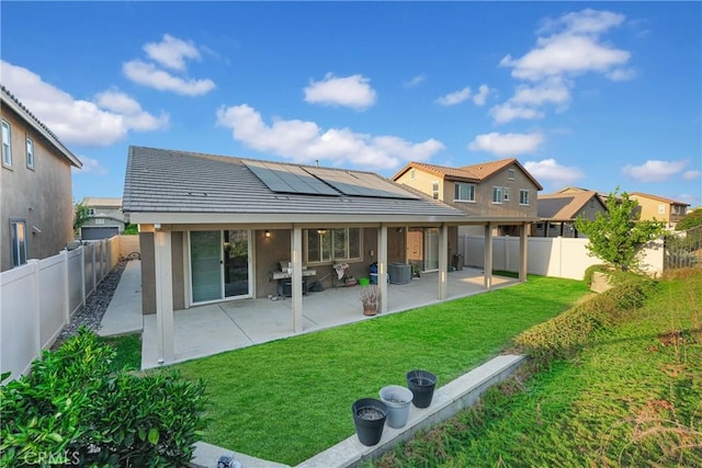 back of house featuring a patio area, solar panels, and a lawn