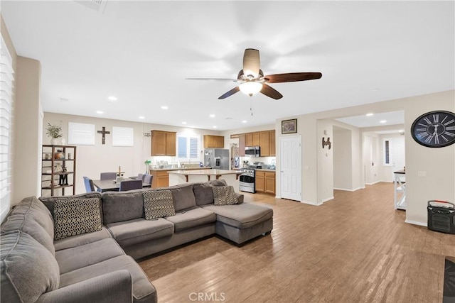 living room featuring ceiling fan and light hardwood / wood-style flooring