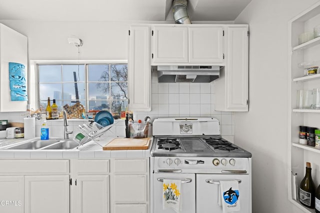 kitchen with double oven range, sink, white cabinets, and decorative backsplash