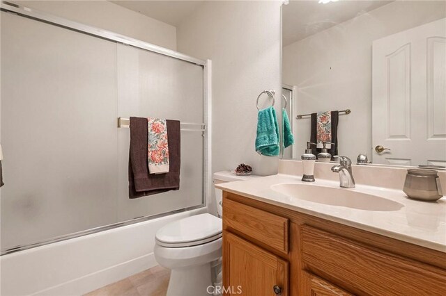 bathroom with vanity, toilet, and shower / bath combination with glass door