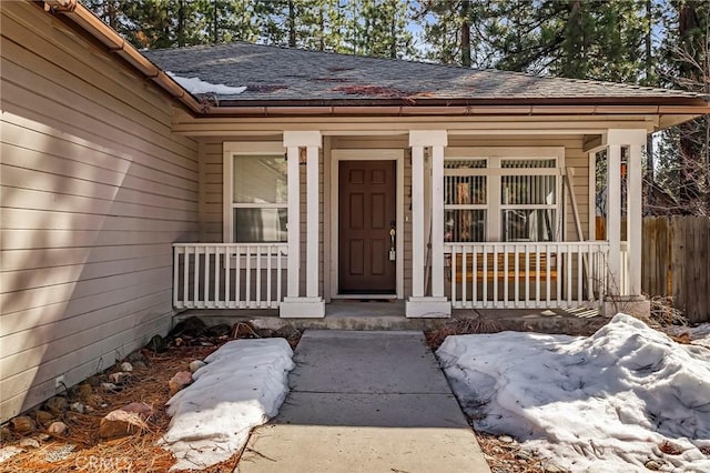 view of exterior entry with a porch and a shingled roof