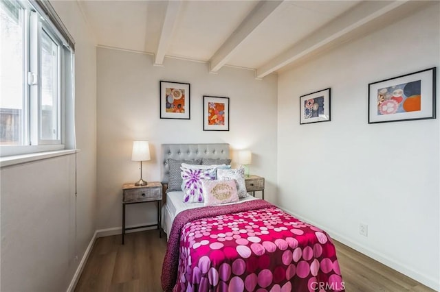 bedroom featuring baseboards, beamed ceiling, and wood finished floors