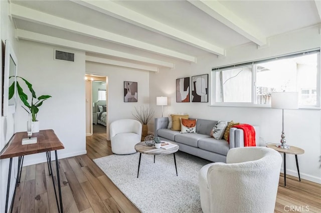 living area featuring beam ceiling, wood finished floors, visible vents, and baseboards